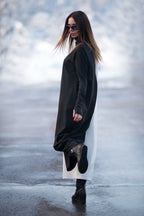 Woman wearing a black dress and sunglasses standing on a snowy surface.