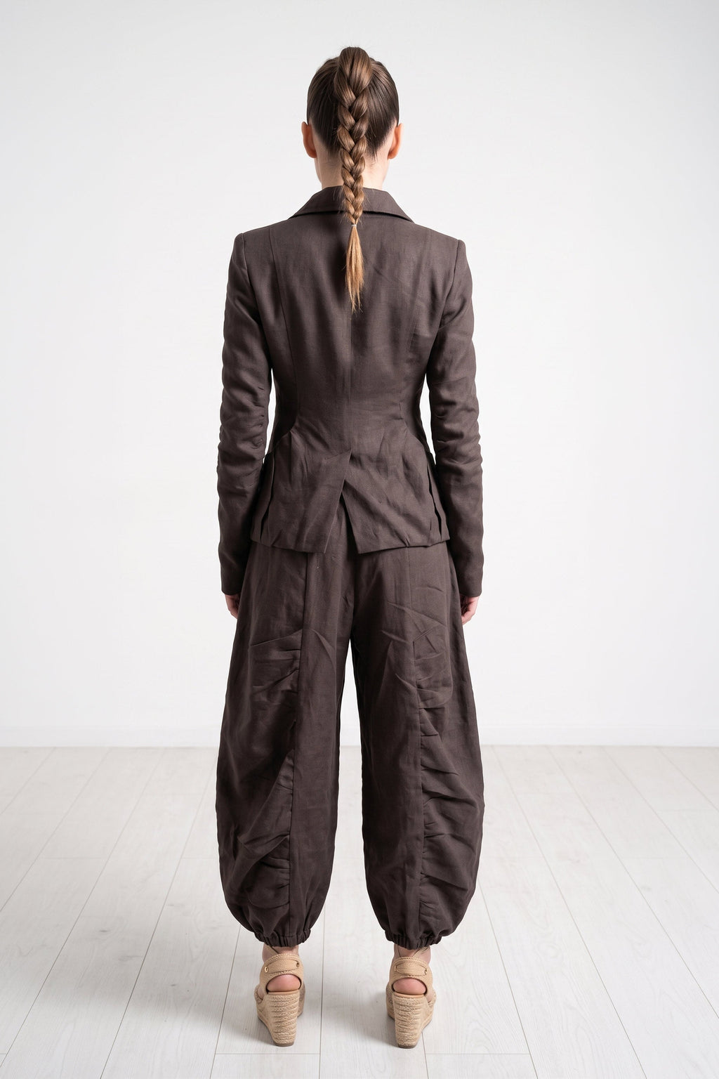Person wearing a brown suit standing on a white floor with a white background