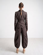 Person wearing a brown suit standing on a white floor with a white background