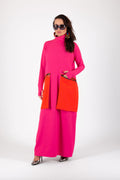 Woman wearing a bright pink dress with orange accents on a white background