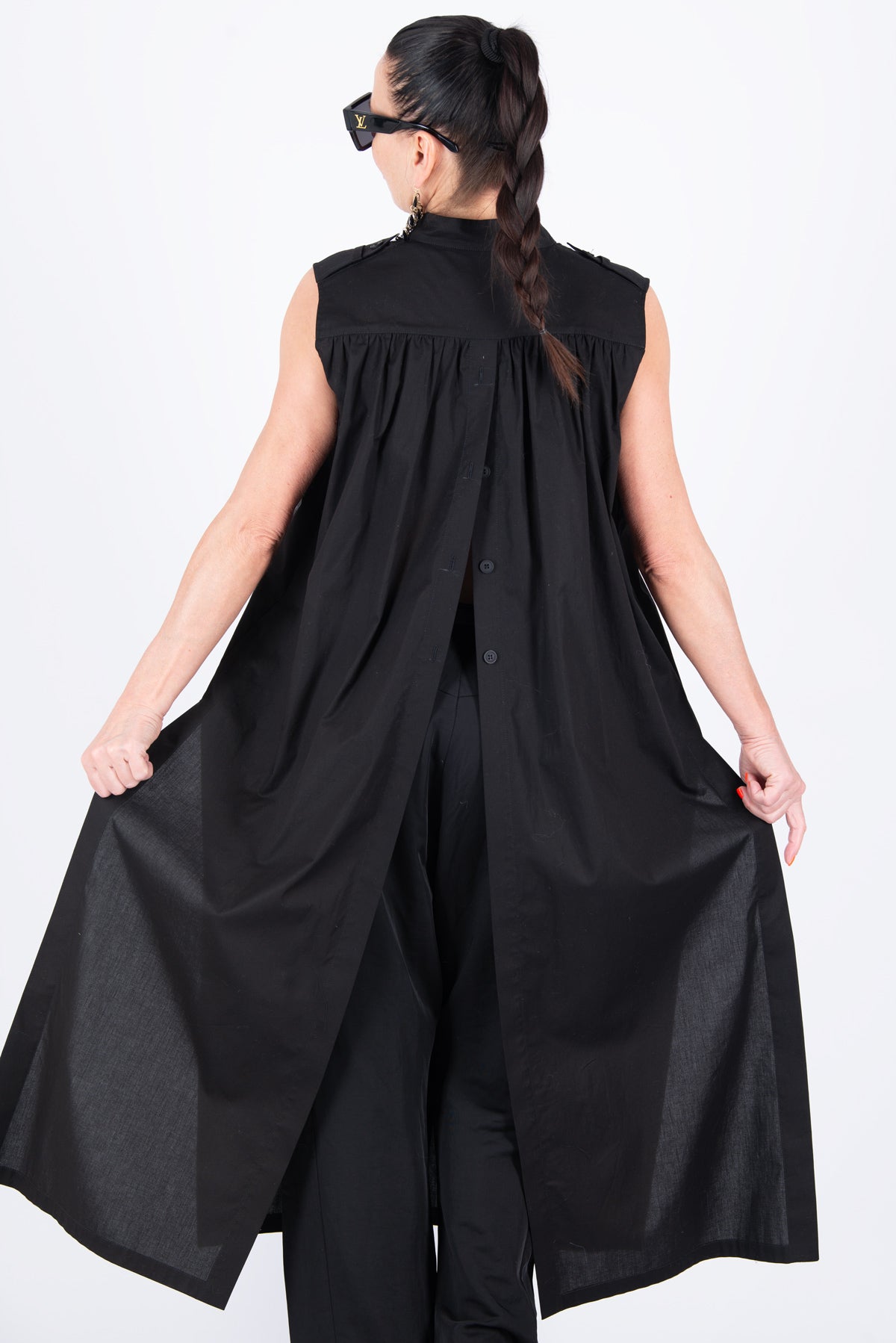 Person wearing a black sleeveless top and wide-leg pants on a white background