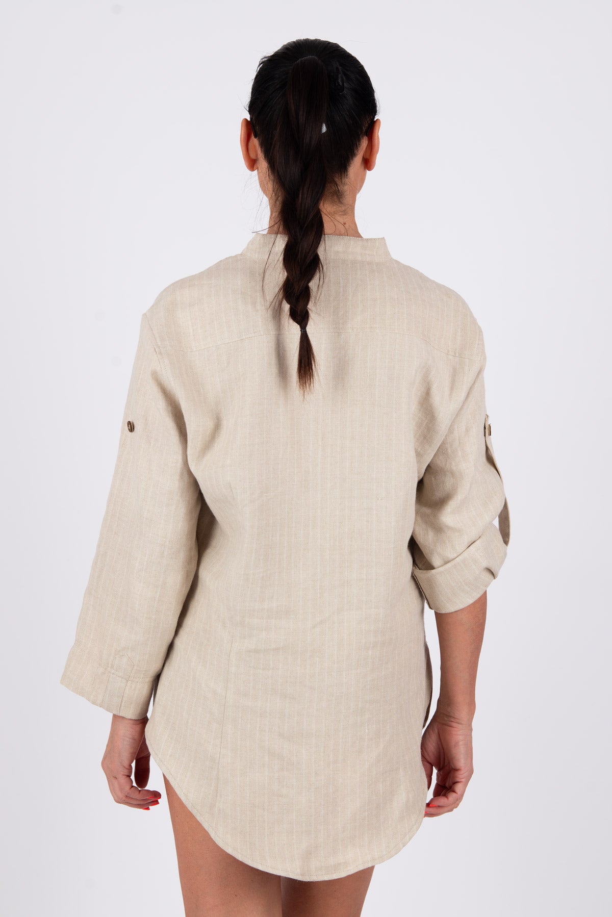 Woman wearing a beige shirt with rolled-up sleeves on a white background