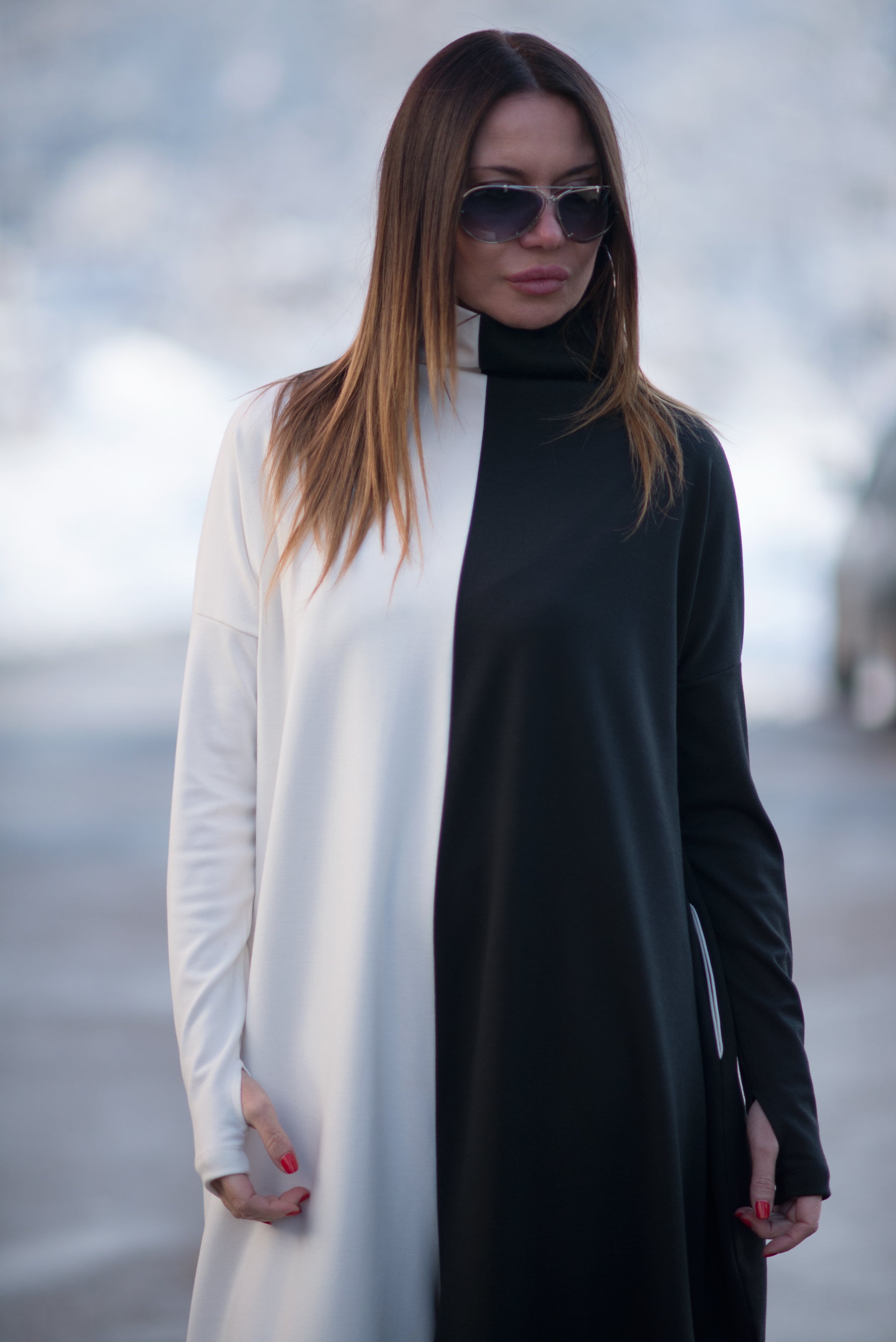 Woman wearing a black and white outfit with sunglasses against a blurred background