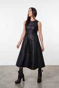 Woman wearing a black dress standing against a white background