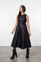 Woman wearing a black dress standing against a white background