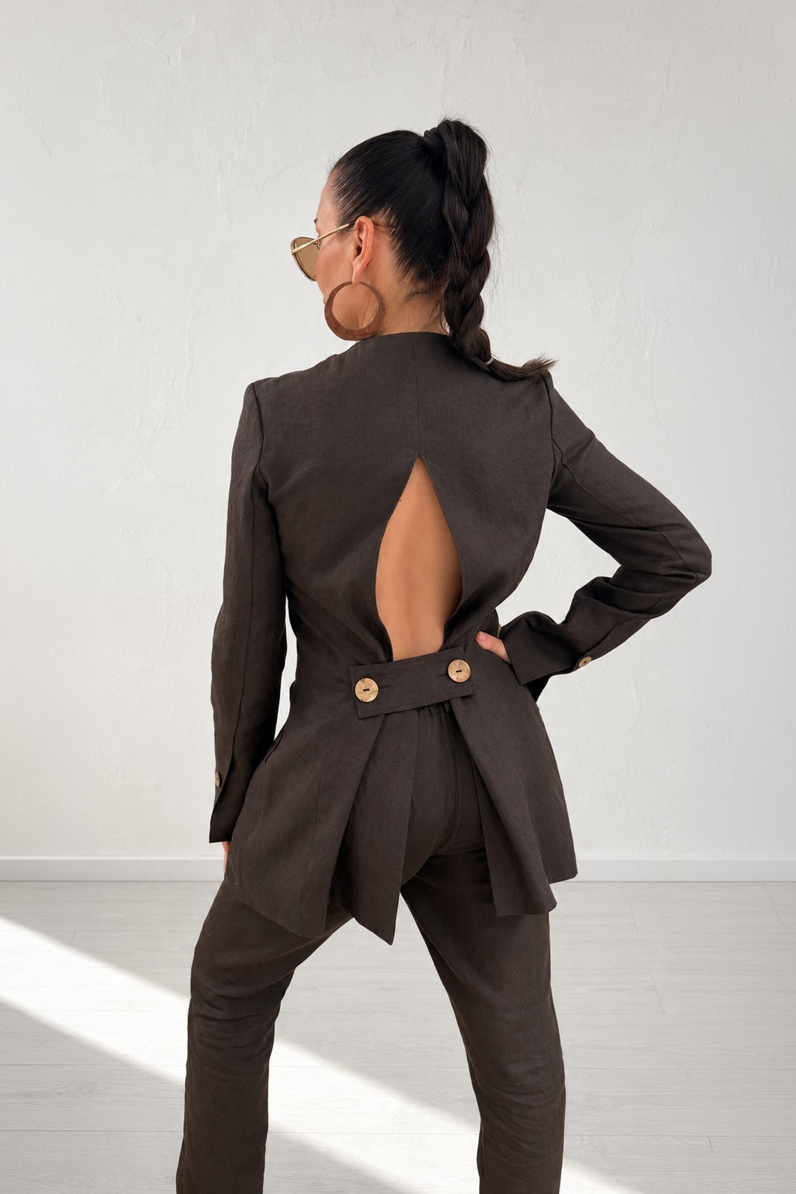 Woman wearing a brown suit with cut-out design on a white background