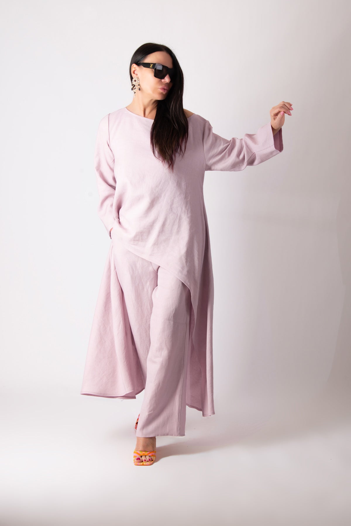 Woman wearing a pink outfit with sunglasses on a white background