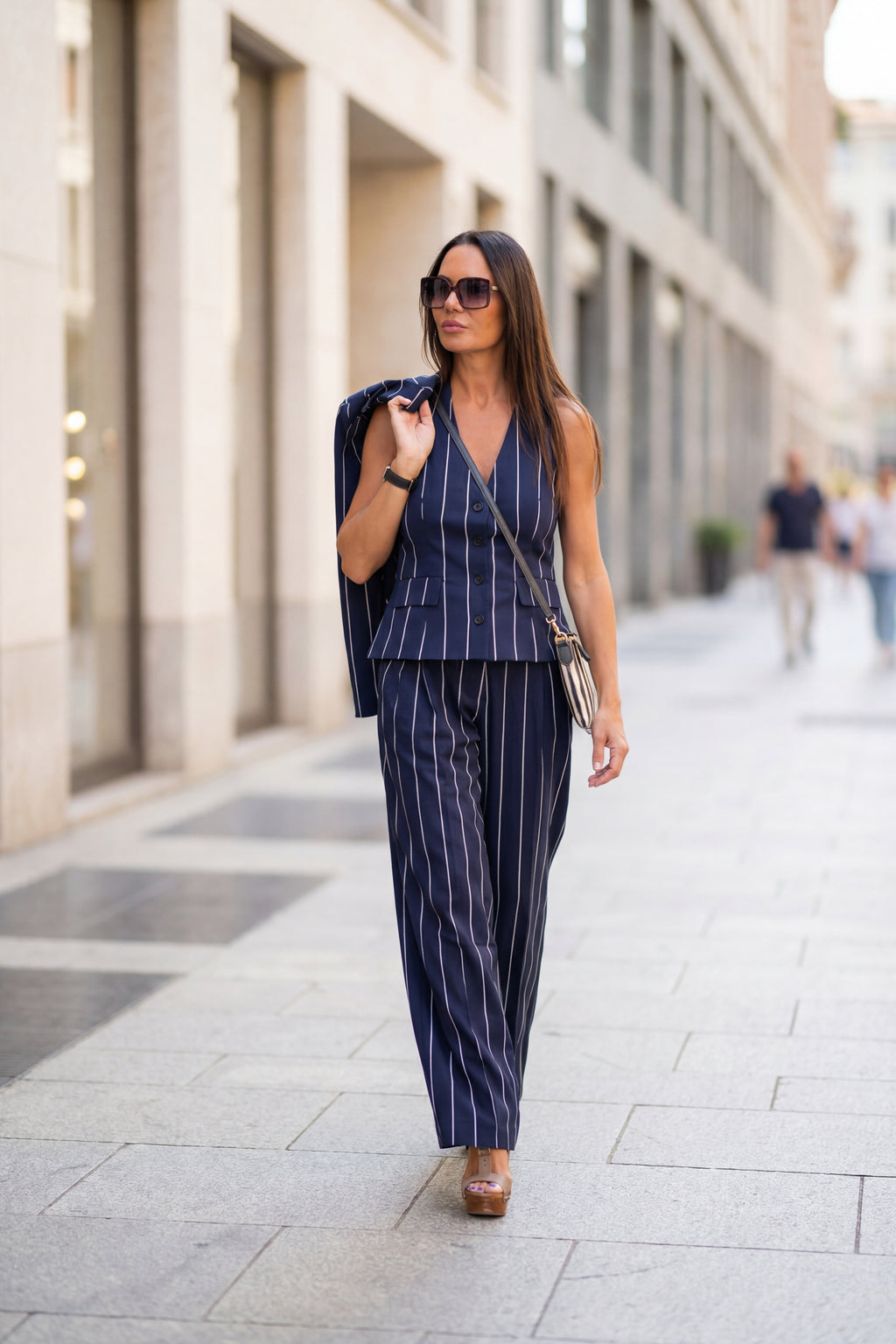 Woman in a navy pinstripe suit walking on a city street.