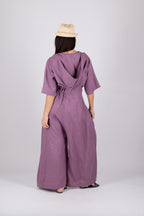 Person wearing a purple jumpsuit with a beige hat on a white background