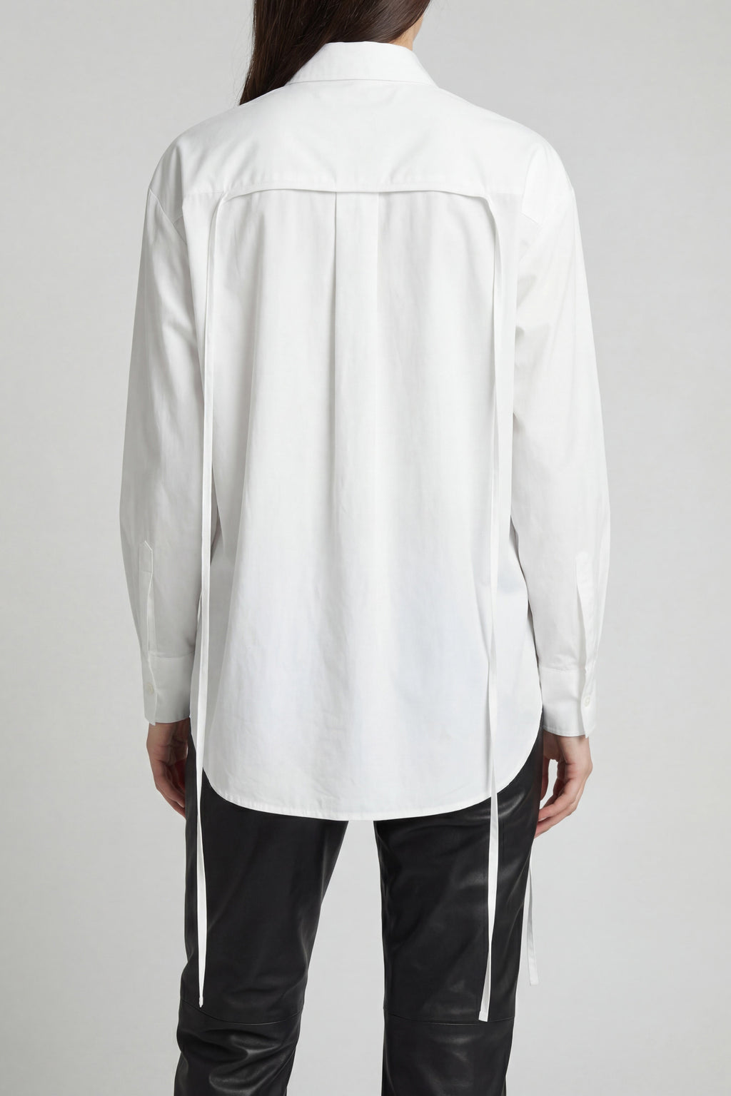 Person wearing a white shirt and black pants on a plain background