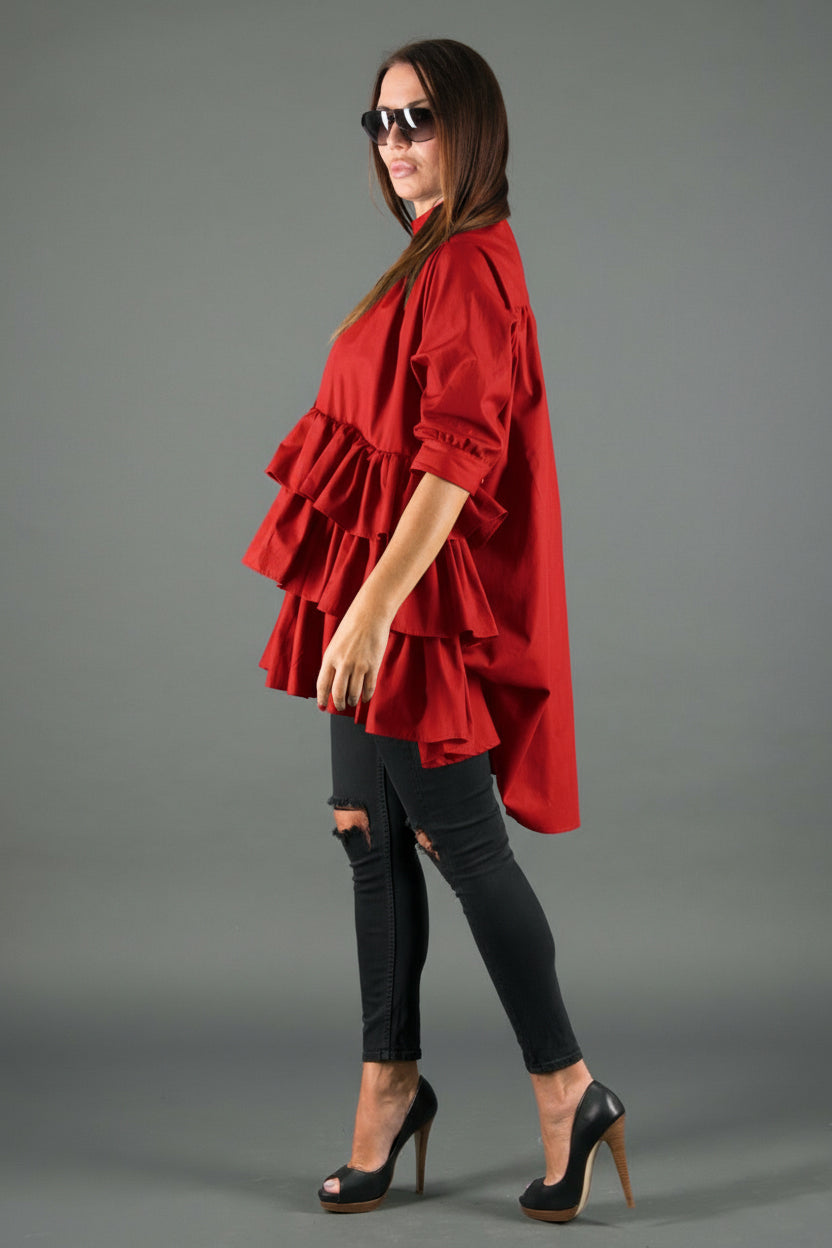 Woman wearing a red ruffled top and black pants on a gray background