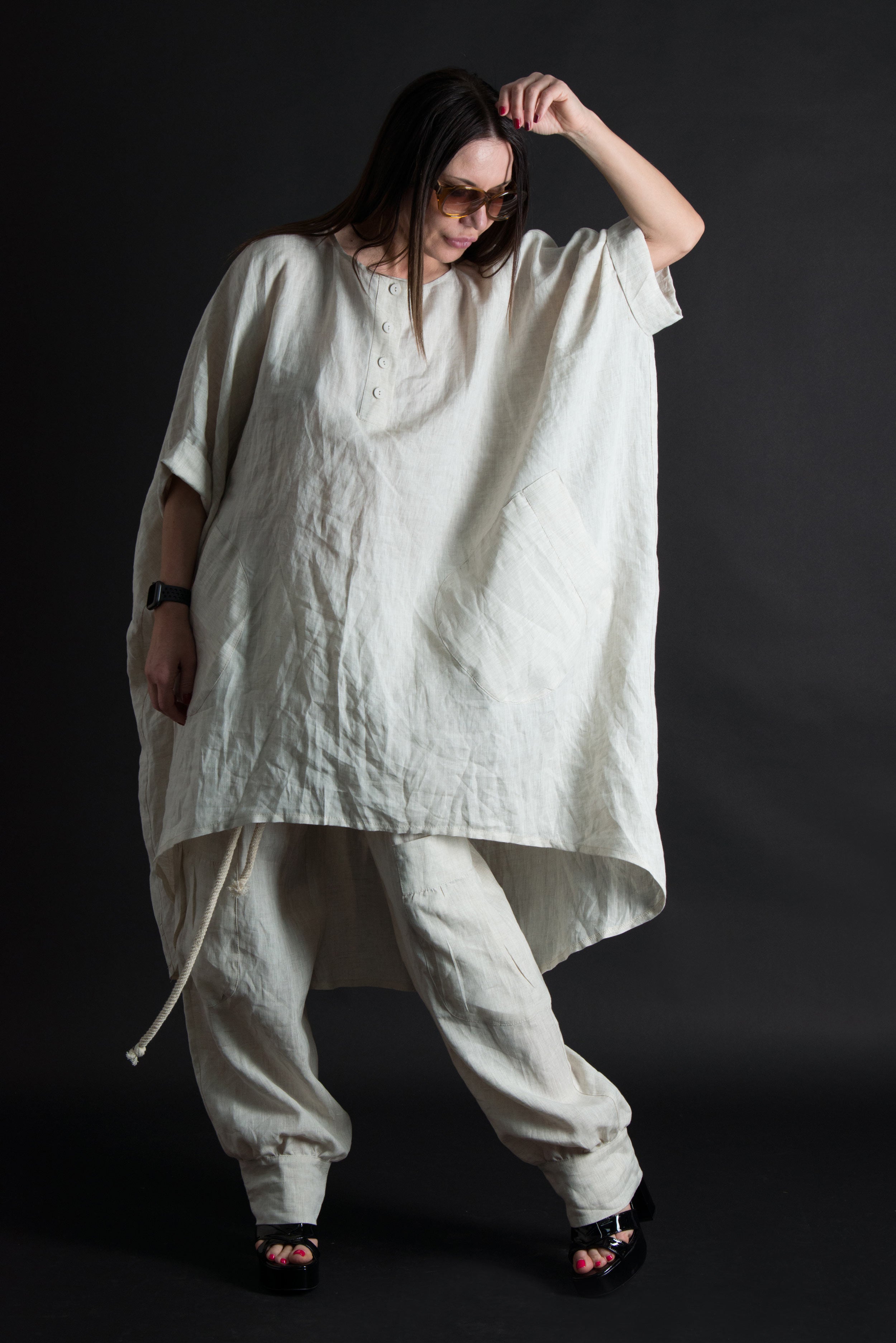 Person wearing a loose-fitting white outfit against a dark background