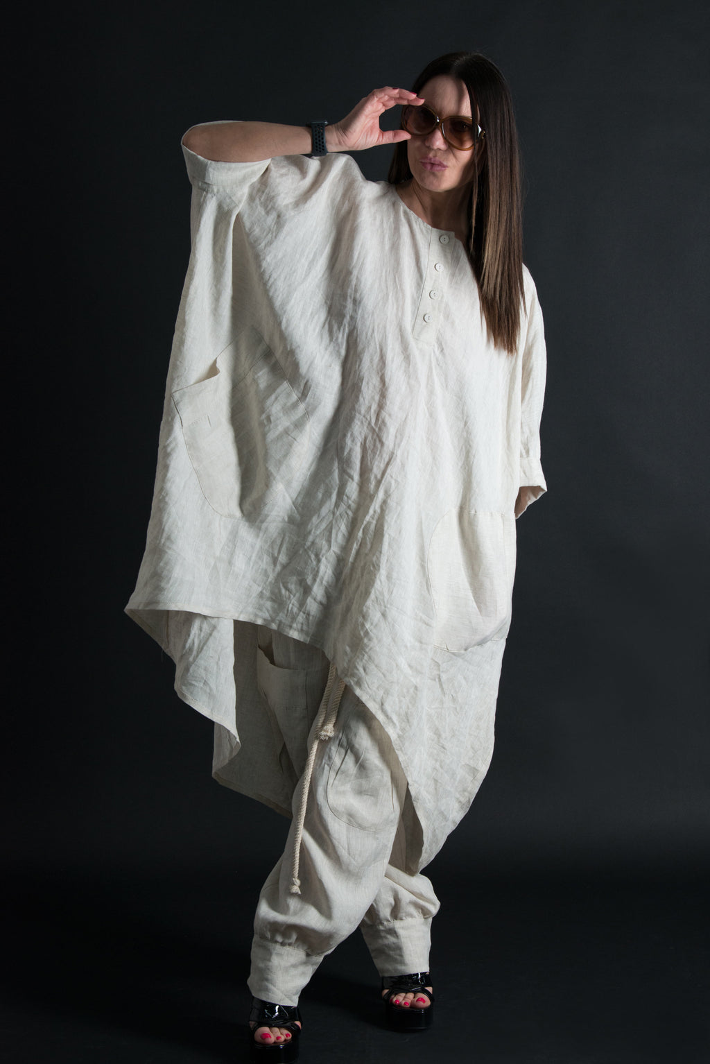 Person wearing a loose-fitting white outfit against a black background