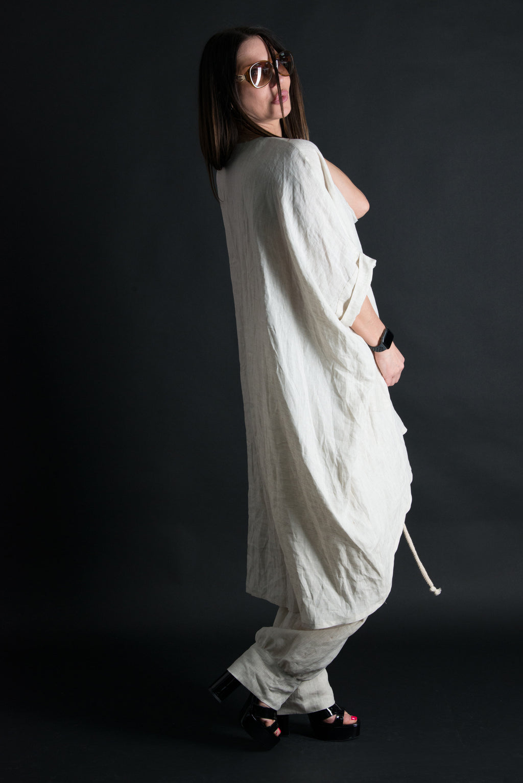 Person wearing a loose-fitting white outfit against a dark background