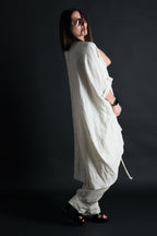 Person wearing a loose-fitting white outfit against a dark background