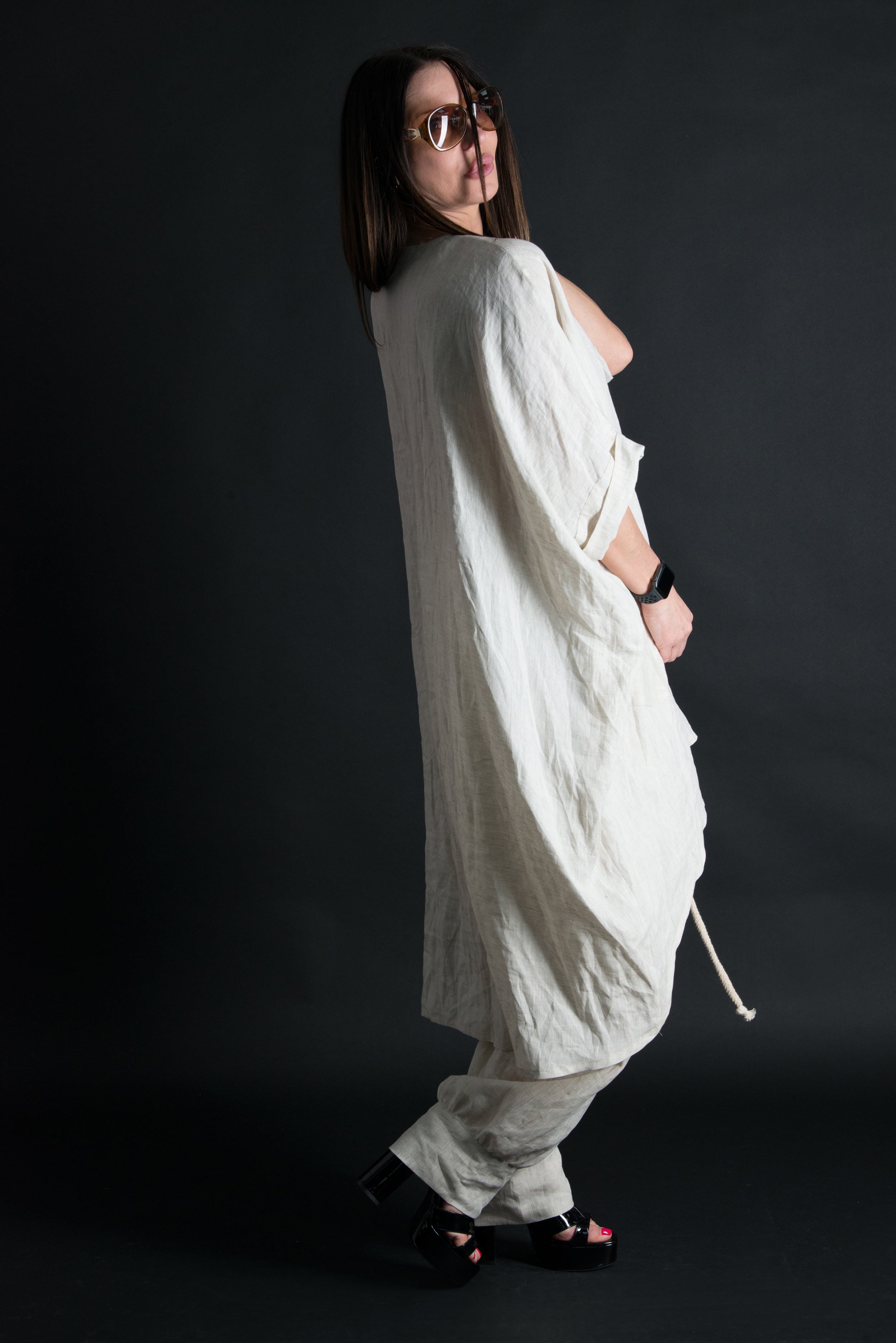 Person wearing a loose-fitting white outfit against a dark background