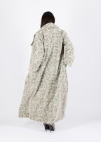Person wearing a long patterned coat on a white background