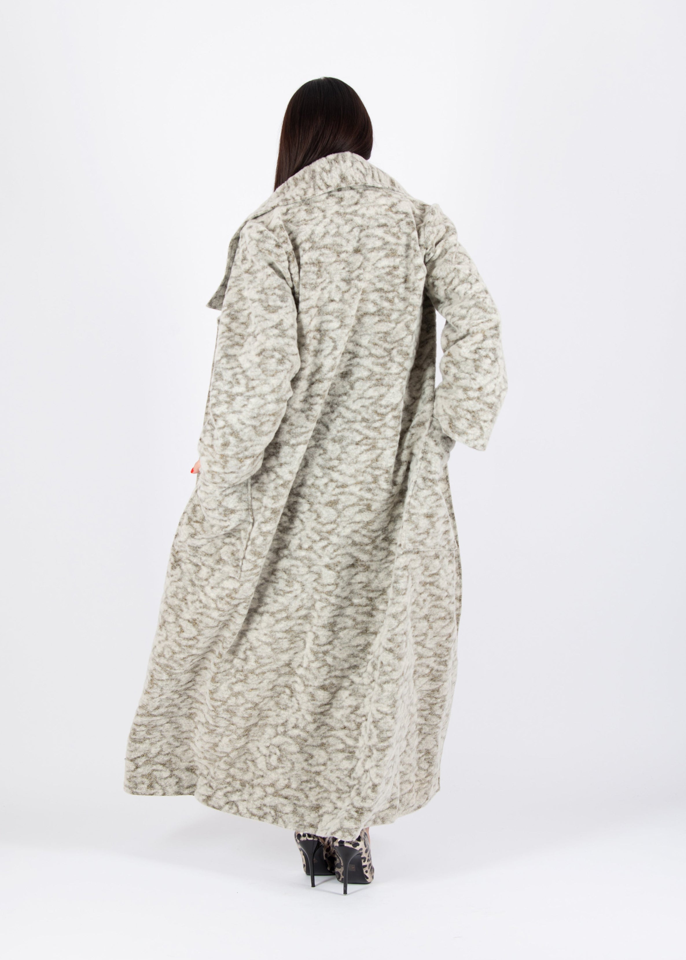 Person wearing a long patterned coat on a white background