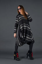 Woman wearing a black and gray plaid dress with sunglasses on a dark background
