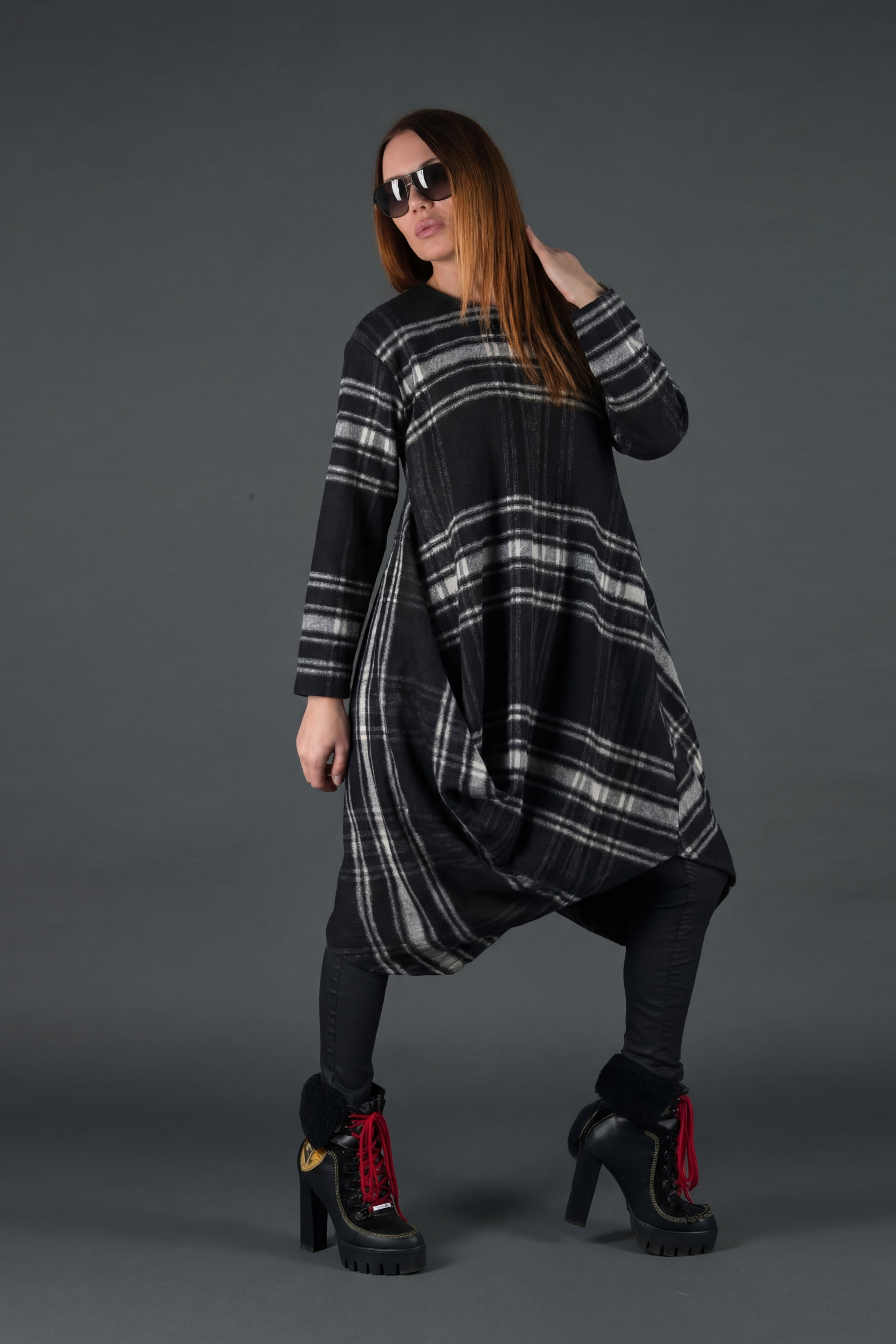 Woman wearing a black and gray plaid dress with sunglasses on a dark background
