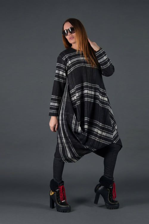 Woman wearing a black and gray plaid dress with sunglasses on a dark background