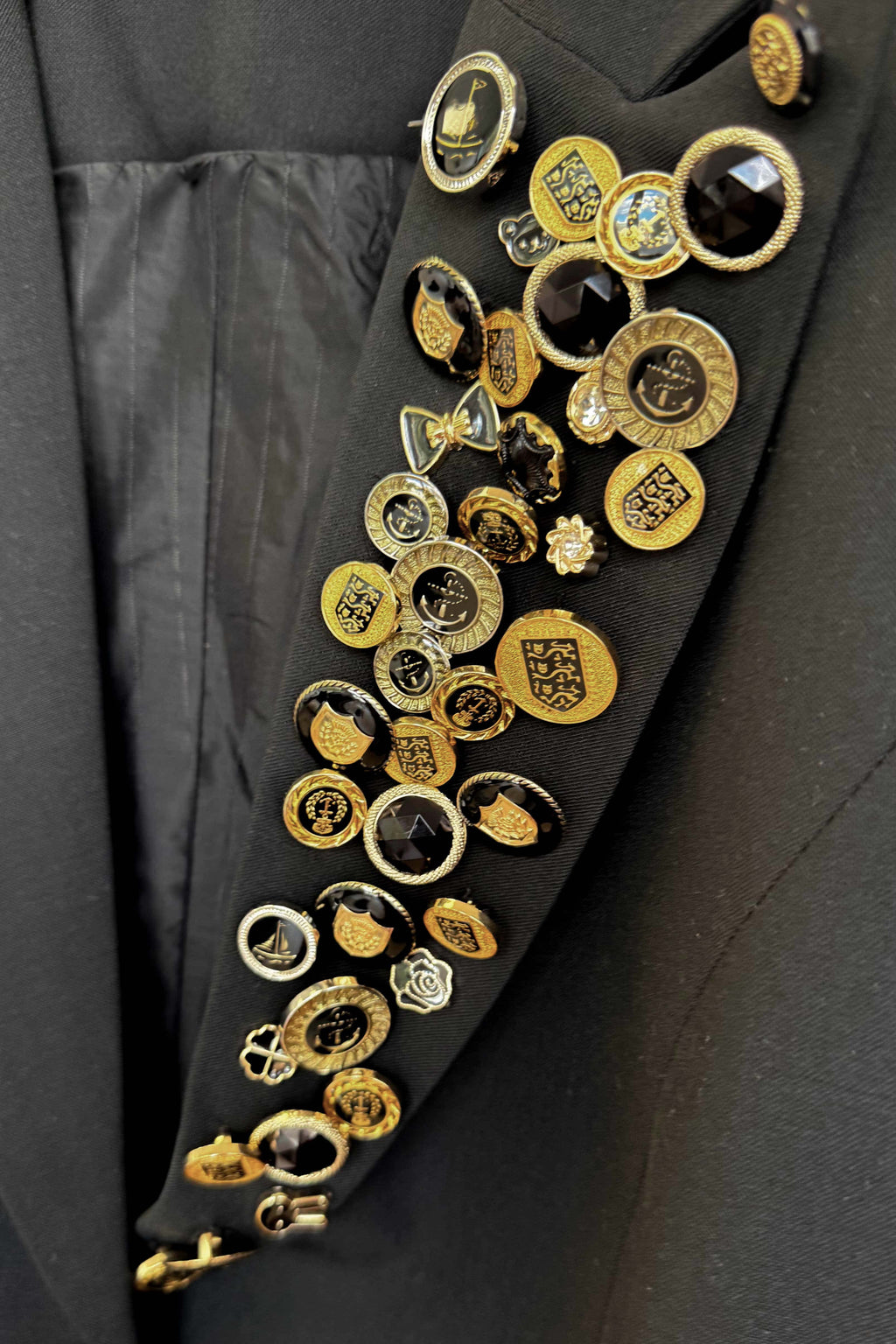 Close-up of a black coat with gold buttons and decorative elements.