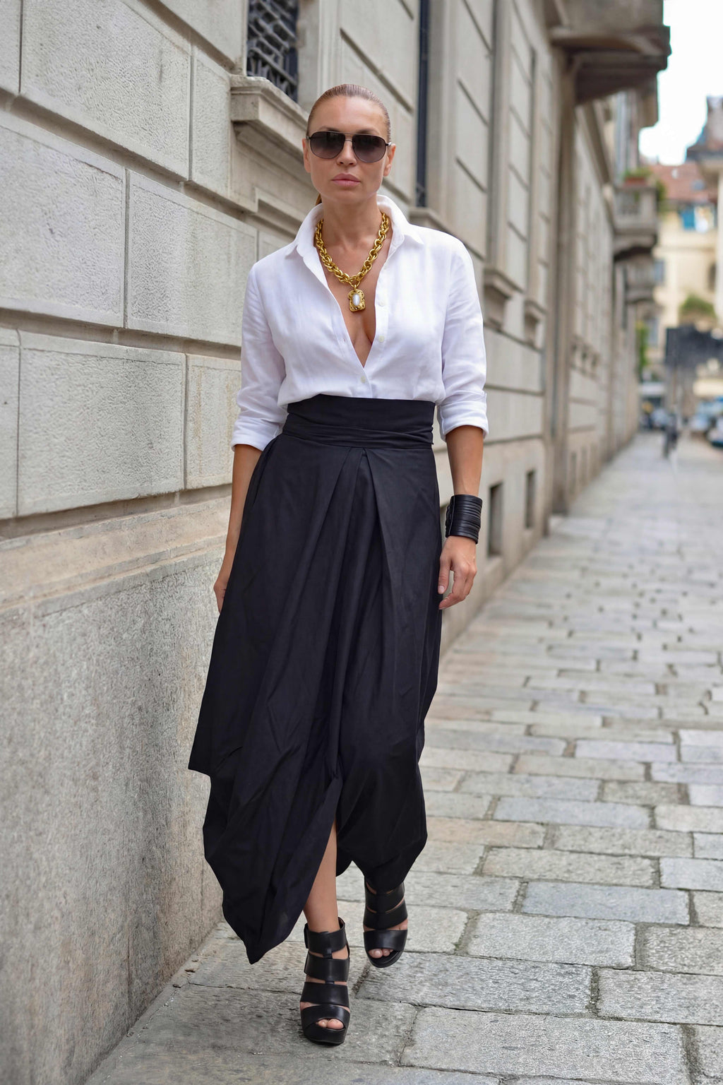 Woman wearing a white shirt and black skirt standing on a city street.