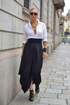 Woman wearing a white shirt and black skirt standing on a city street.