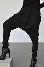 Person wearing black harem pants and high-heeled boots on a plain background