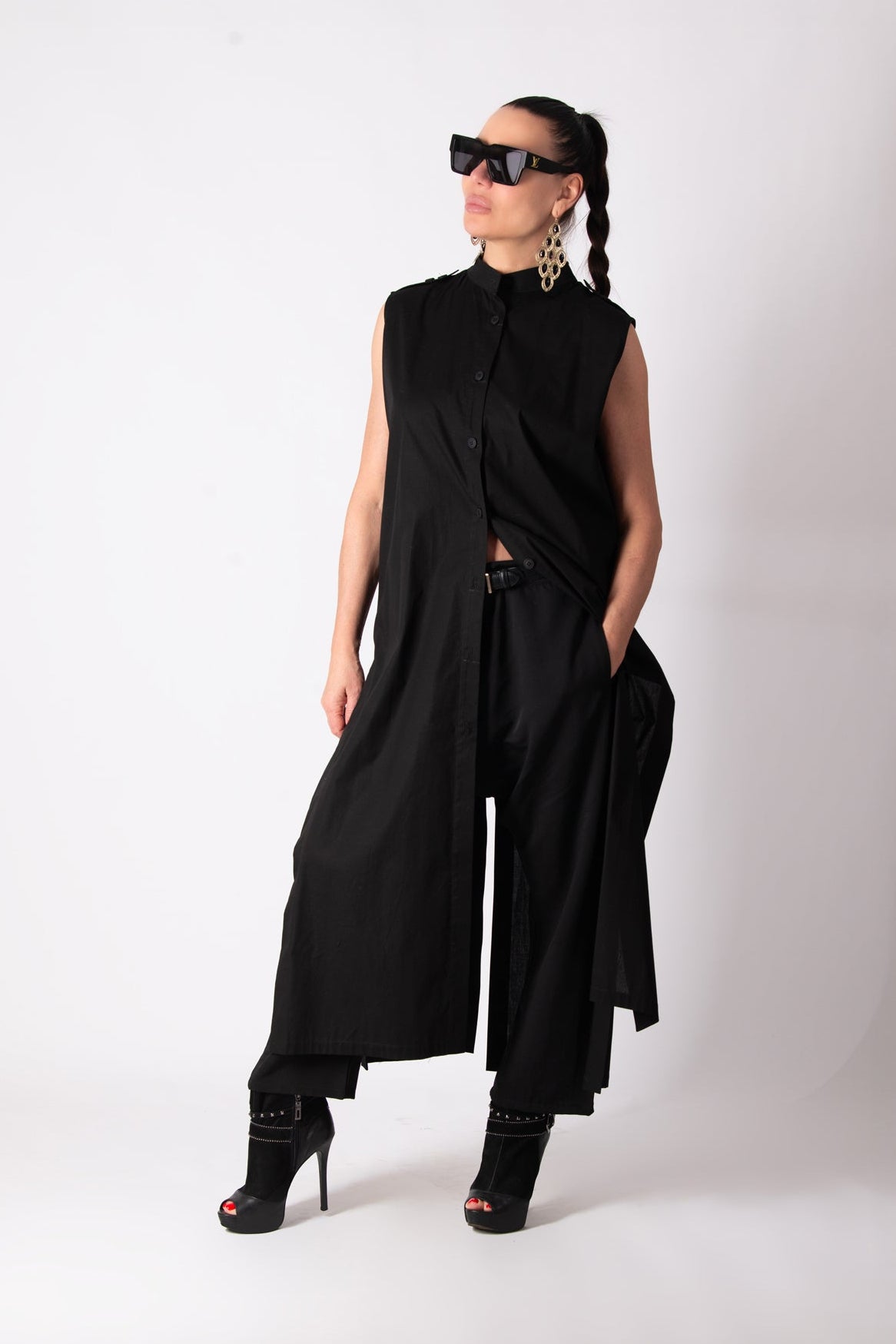 Person wearing a black sleeveless top and wide-leg pants on a white background