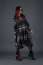 Woman wearing a black and gray plaid dress with high-heeled shoes on a gray background