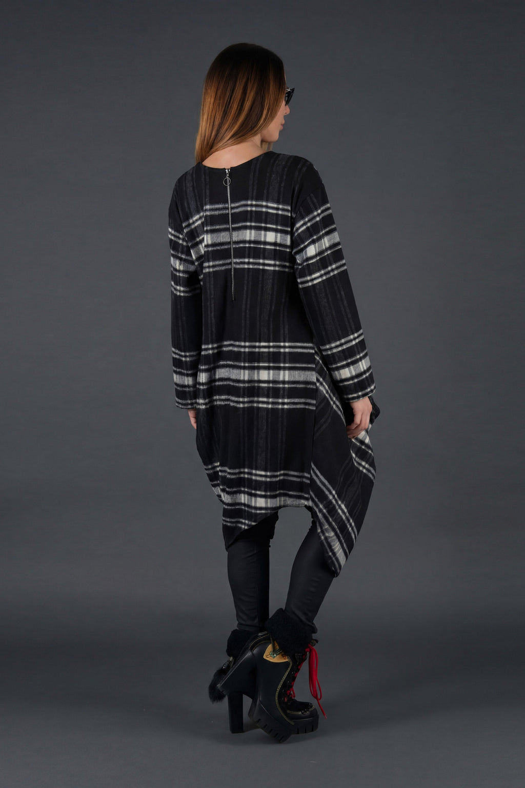 Woman wearing a black and gray plaid dress on a gray background