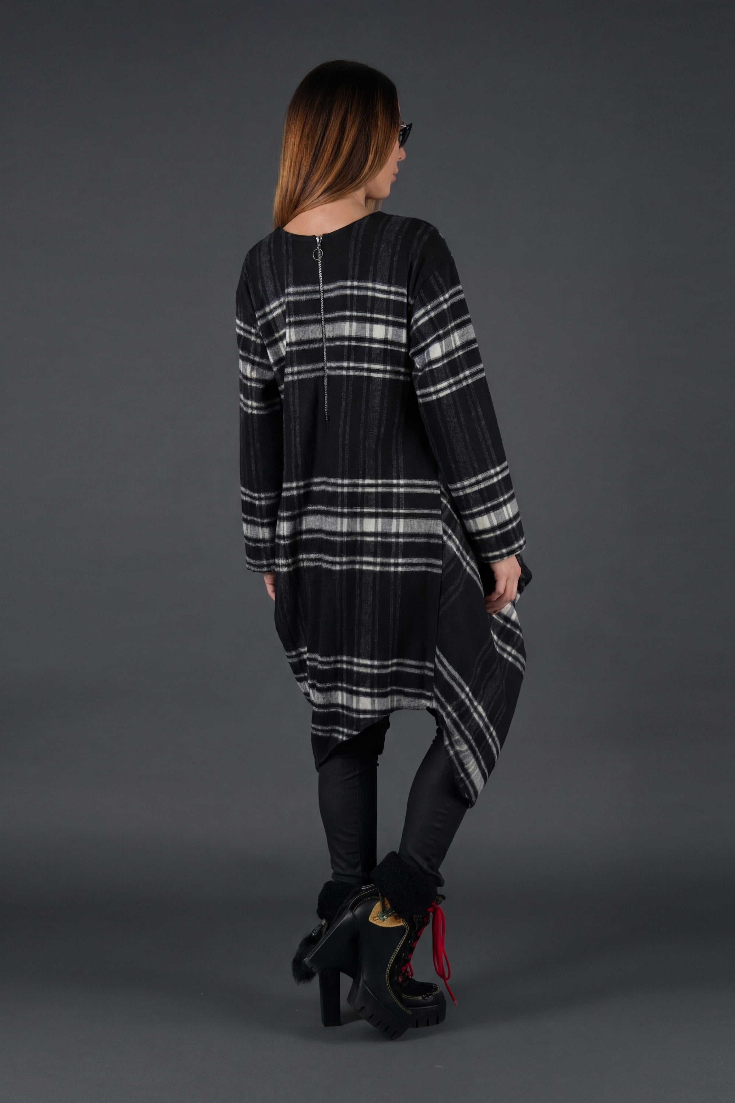 Woman wearing a black and gray plaid dress on a gray background