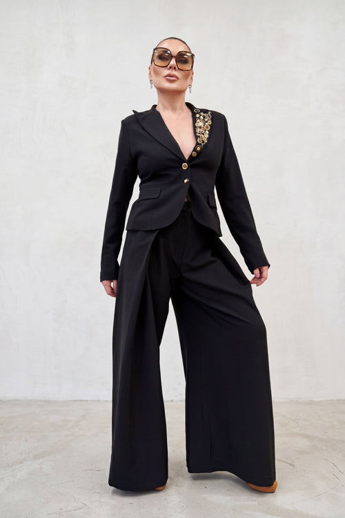 Person wearing a black suit with floral embellishments on a white background