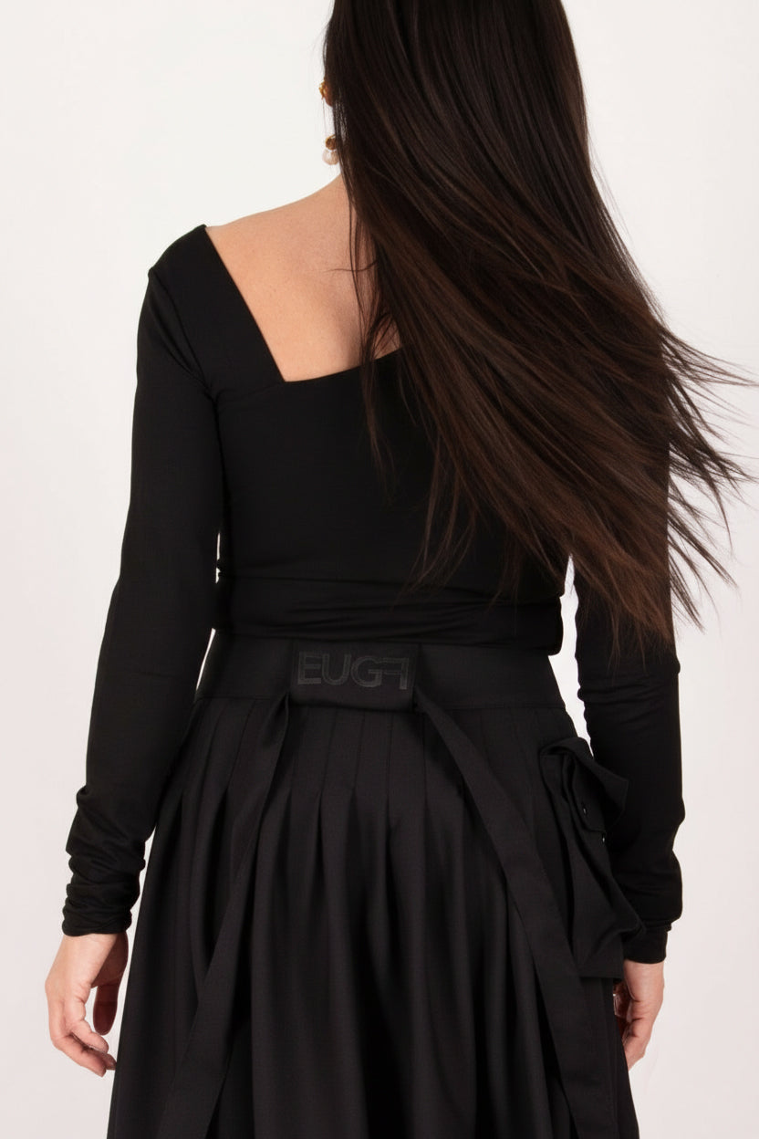 Person wearing a black dress with a brand logo on a light pink background
