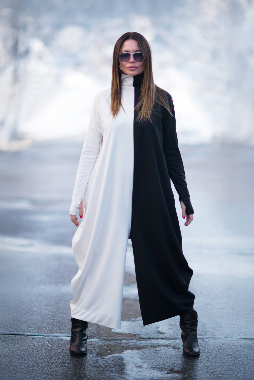 Woman wearing a long black and white dress with sunglasses on a blurred outdoor background