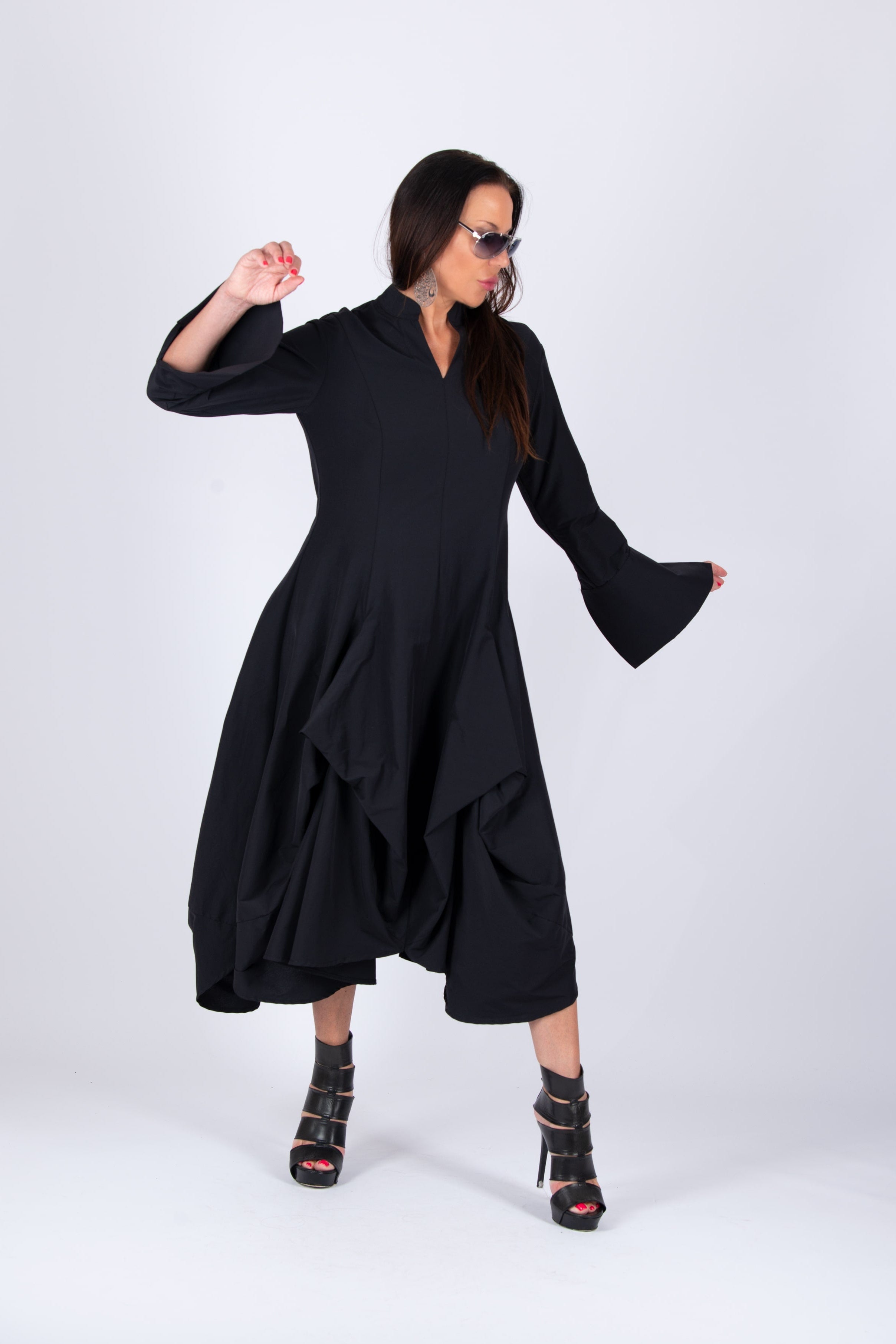 Woman wearing a black dress with bell sleeves on a white background