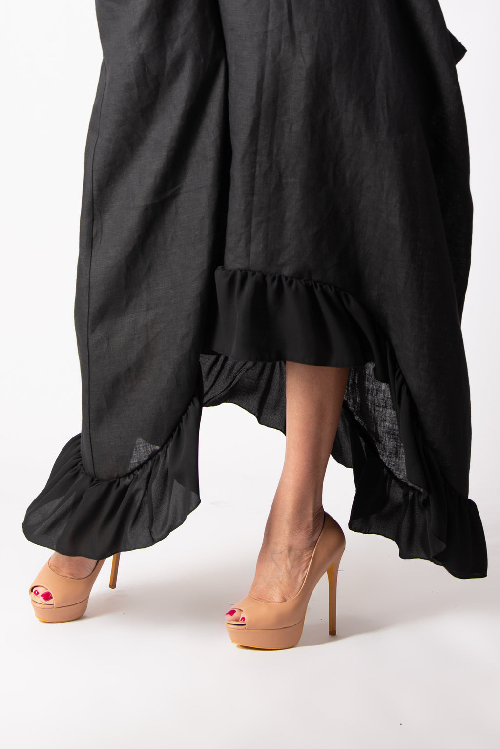 Black ruffled skirt worn by a person on a white background
