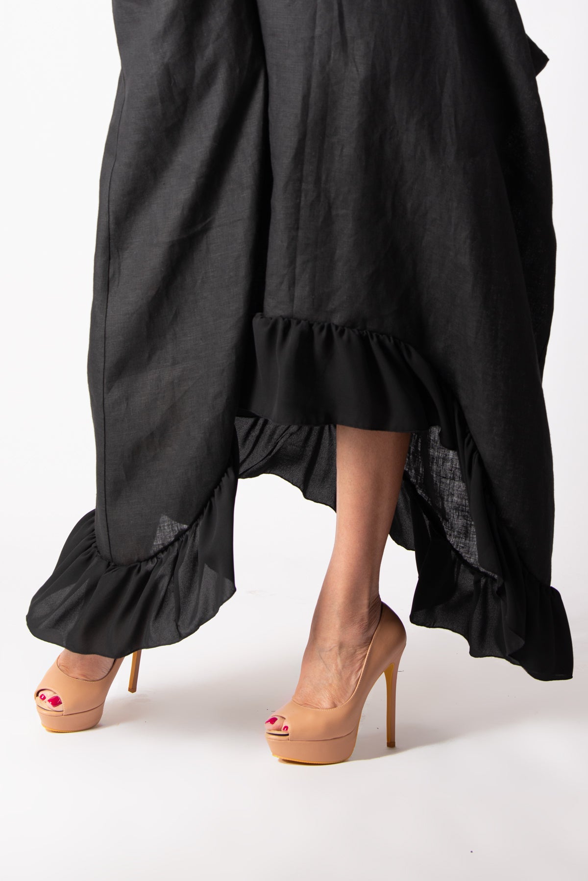 Black ruffled skirt worn by a person on a white background