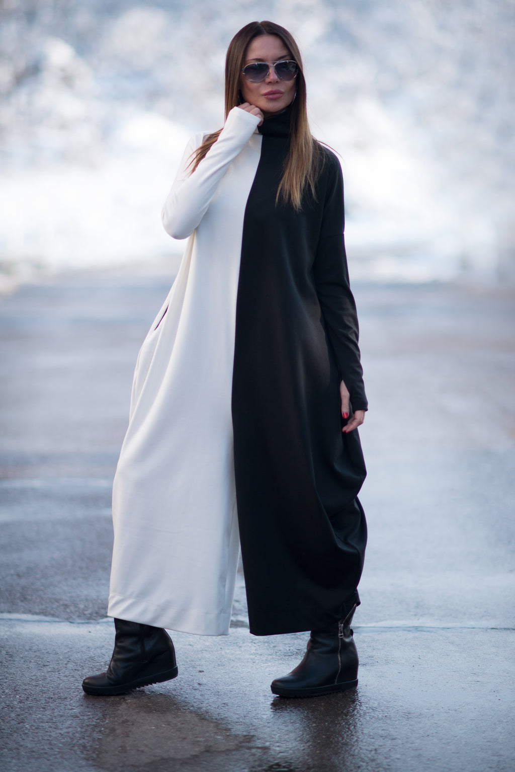 Woman wearing a long black and white dress with sunglasses on a blurred background