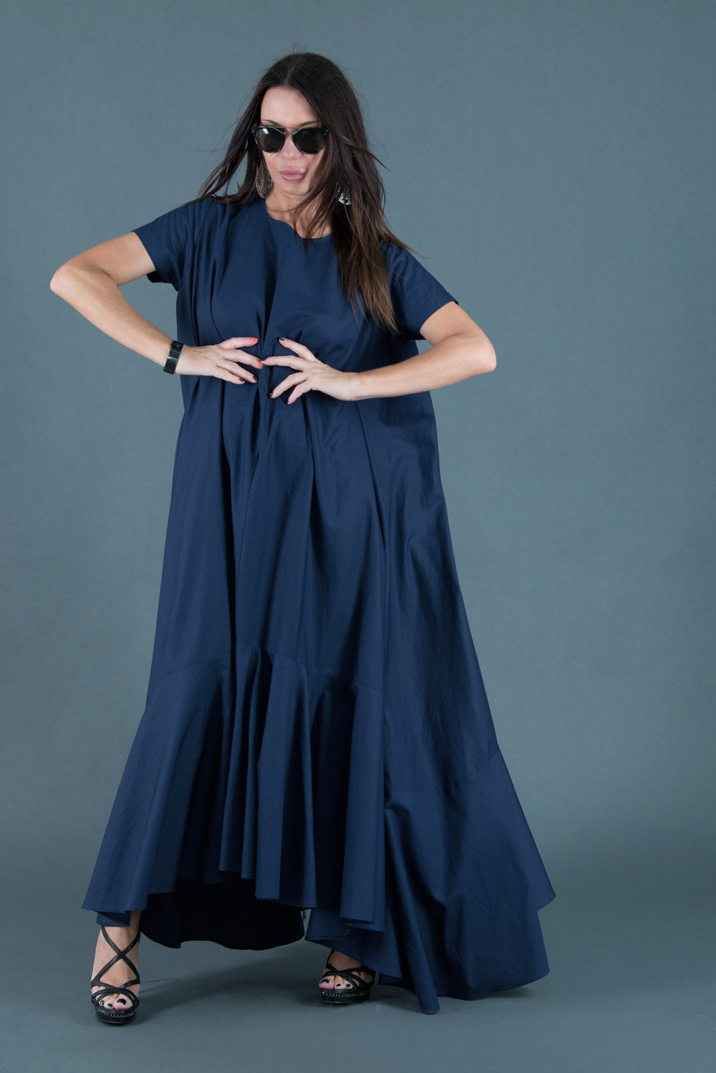 Woman wearing a long navy dress against a gray background