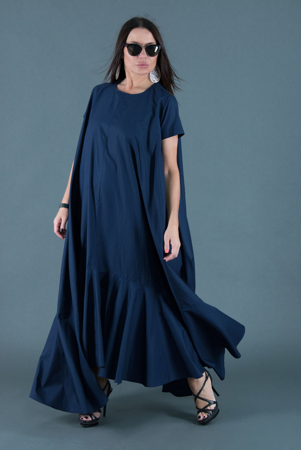 Woman wearing a long navy dress against a gray background