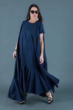 Woman wearing a long navy dress against a gray background