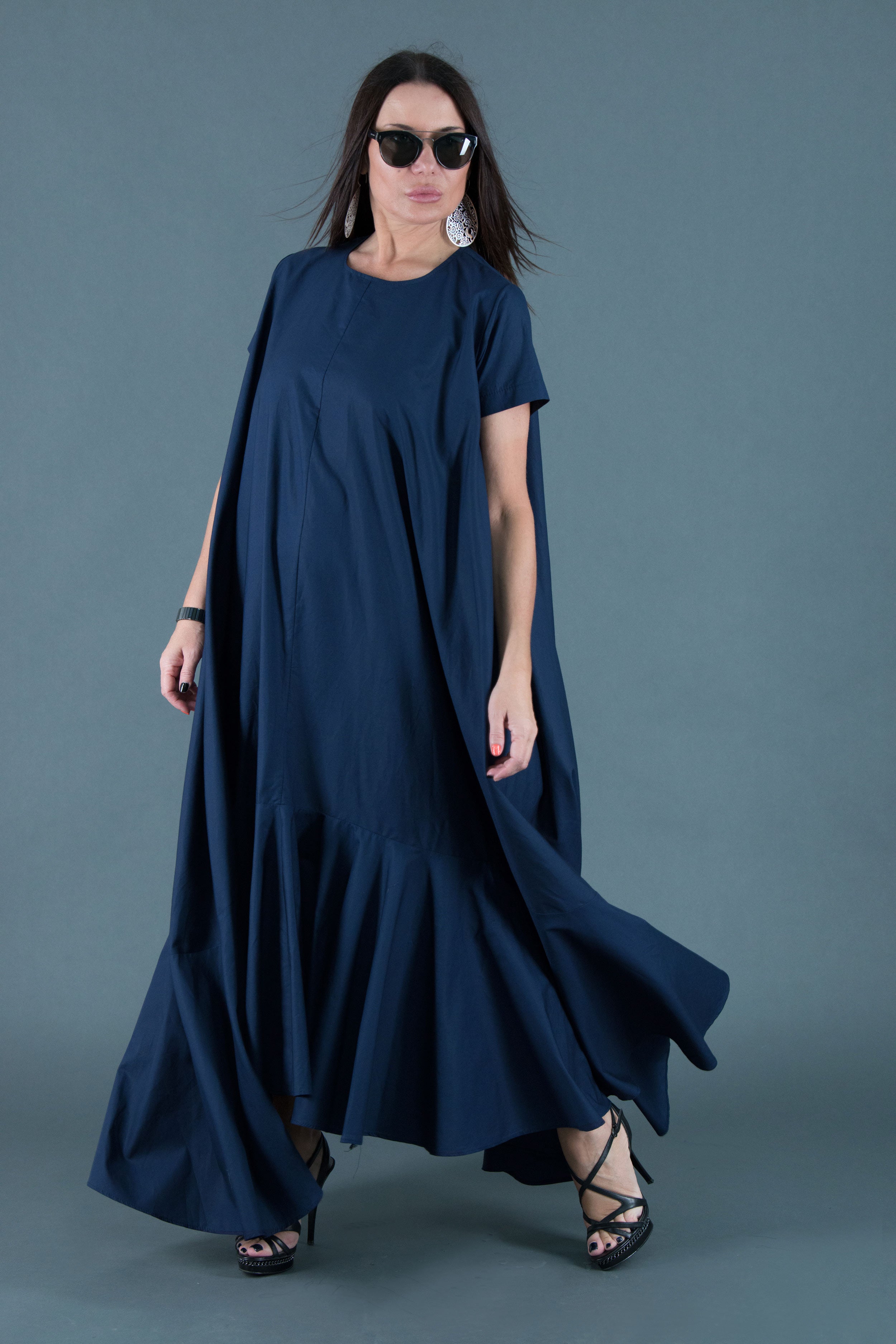 Woman wearing a long navy dress against a gray background