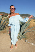 Woman in a light blue dress standing outdoors with mountains in the background