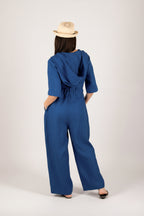 Person wearing a blue jumpsuit with a beige hat on a white background