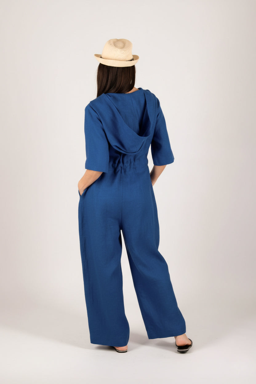 Person wearing a blue jumpsuit with a beige hat on a white background