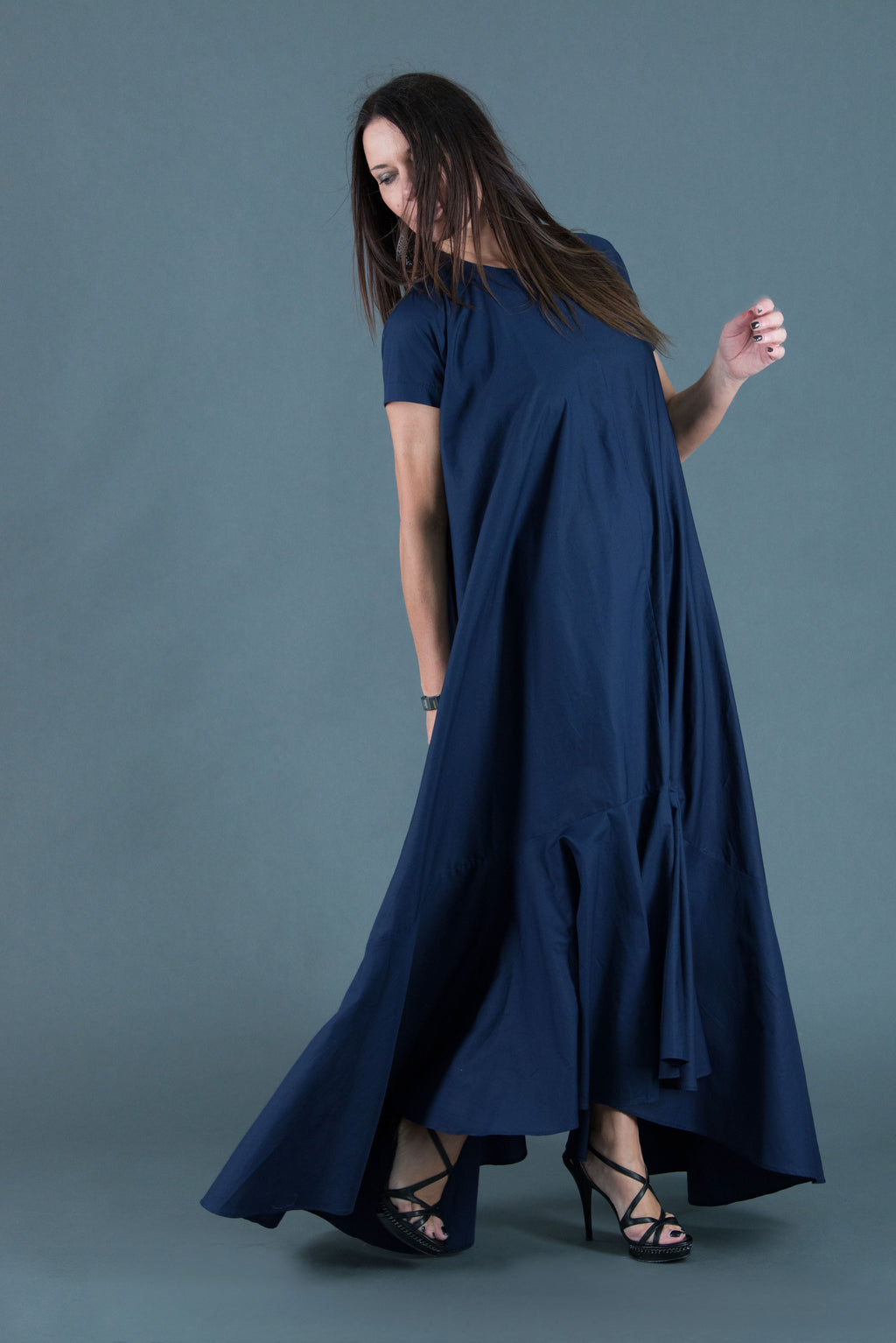 Woman wearing a long navy blue dress against a gray background