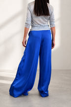 Person wearing blue wide-leg pants and a gray top on a plain background