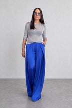 Woman wearing a gray top and blue pants against a plain background